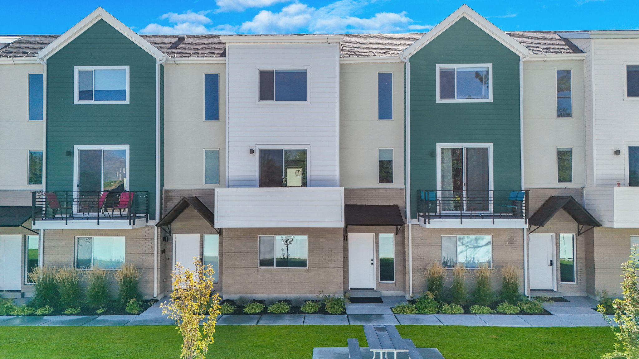 View of front facade featuring a balcony, brick siding, and a front lawn