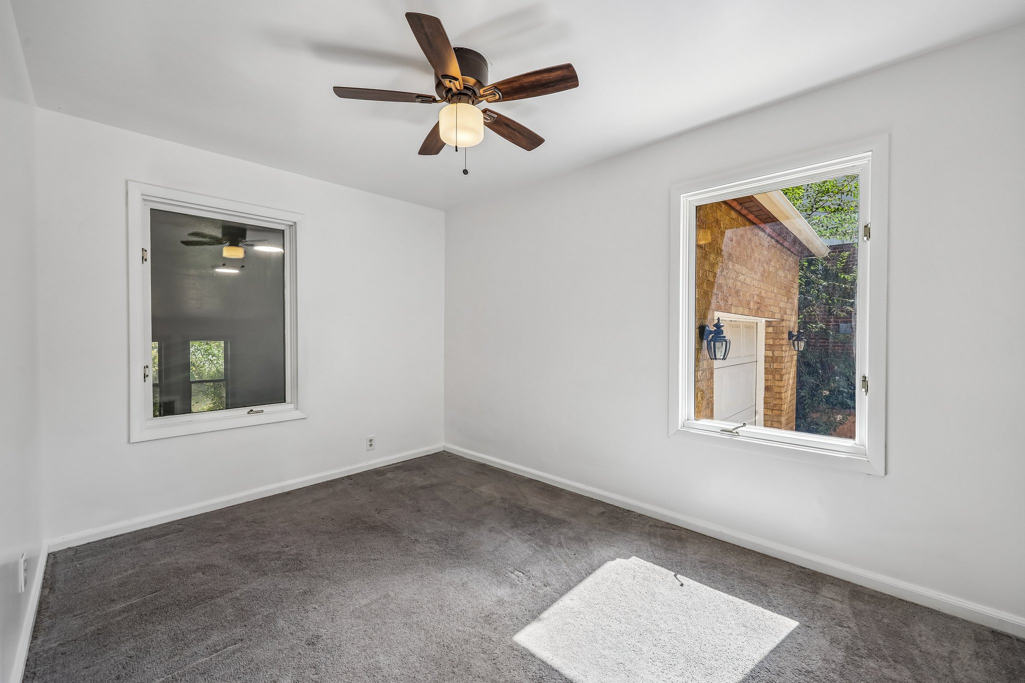 Interior space featuring clean white walls, gray carpet, a ceiling fan with integrated lighting, and two white-framed windows