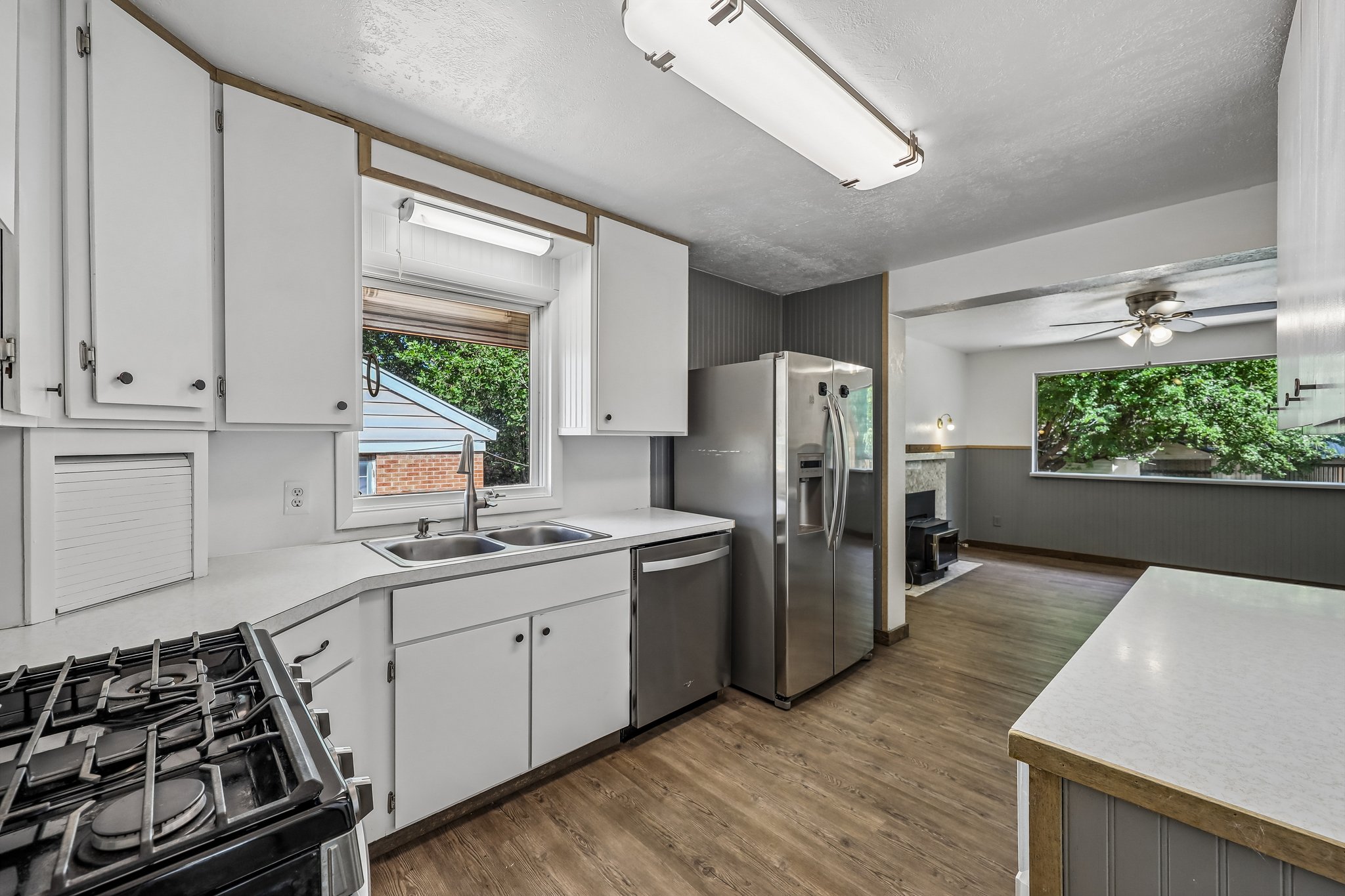 Kitchen featuring white cabinetry, a double basin stainless steel sink, a stainless steel refrigerator, and wood-finish flooring