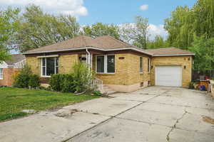 Ranch-style house with a garage, brick siding, concrete driveway, and a front lawn