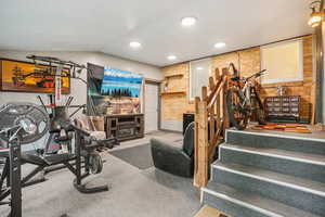 Workout area with lofted ceiling, recessed lighting, brick wall, and a fireplace