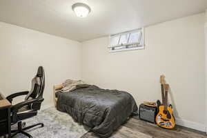 Bedroom featuring an office area, a textured ceiling, and wood finished floors