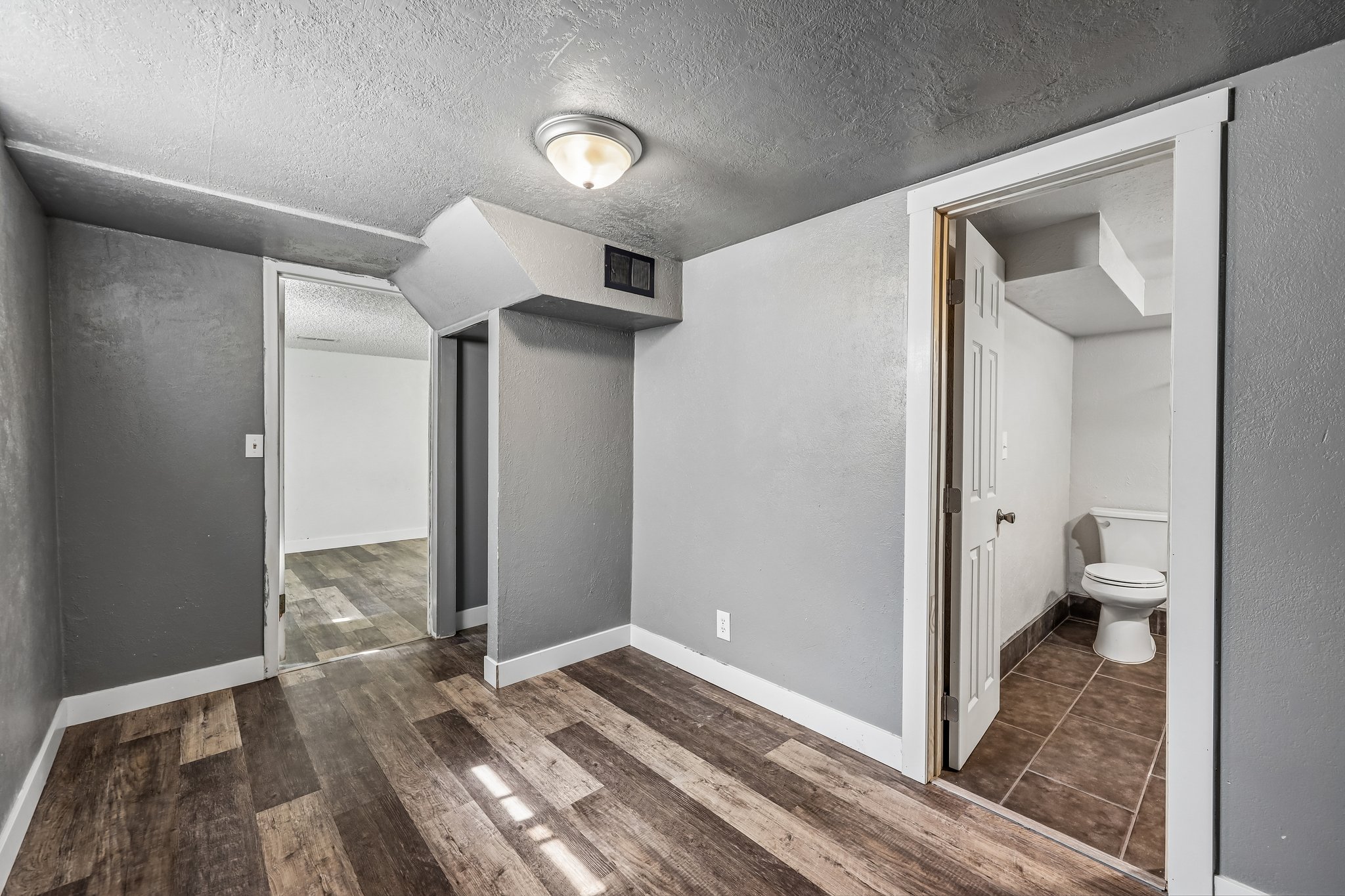 Room featuring wood-finish flooring, light gray wall paint, and white baseboards