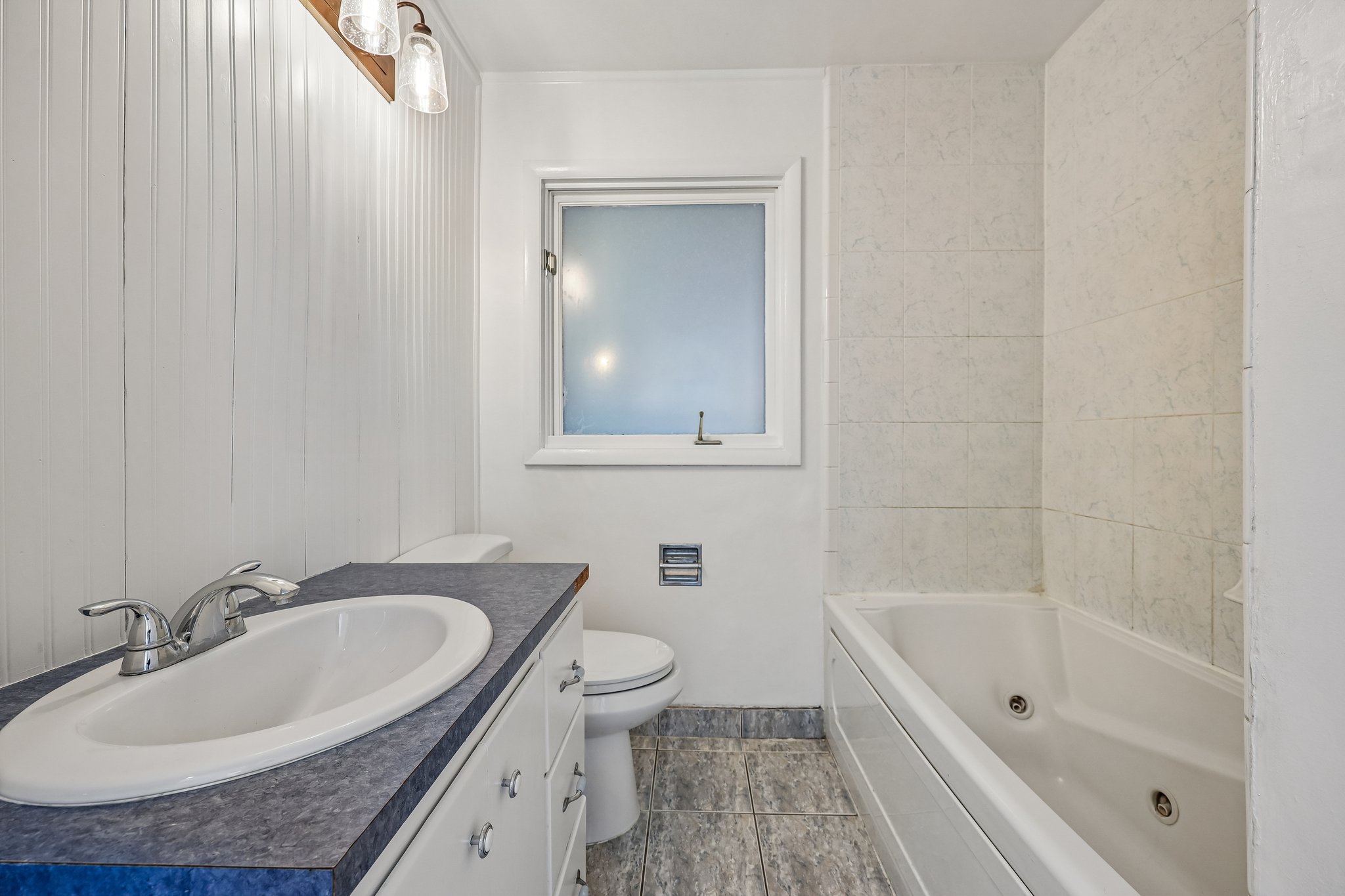 Bathroom featuring a white vanity with an undermount sink, a blue speckled countertop, and chrome fixtures