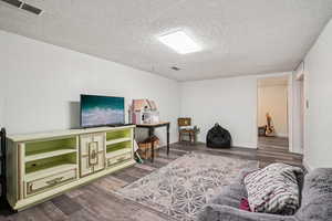 Living area featuring dark wood finished floors and a textured ceiling