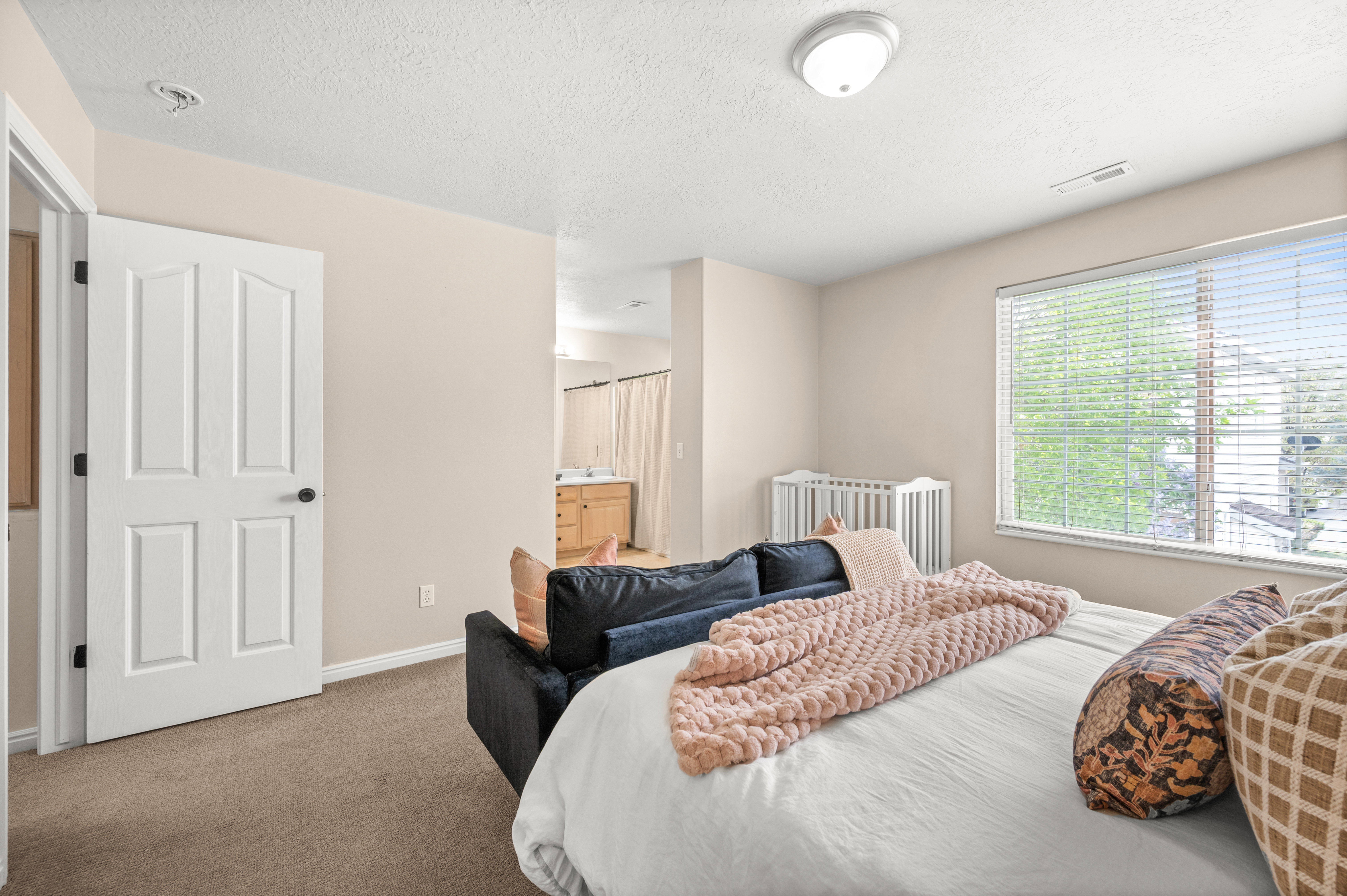 Carpeted bedroom featuring connected bathroom and a textured ceiling