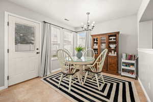 Dining space with a textured ceiling, suspended lighting, and light tile patterned floors