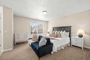 Carpeted bedroom featuring a textured ceiling and baseboards