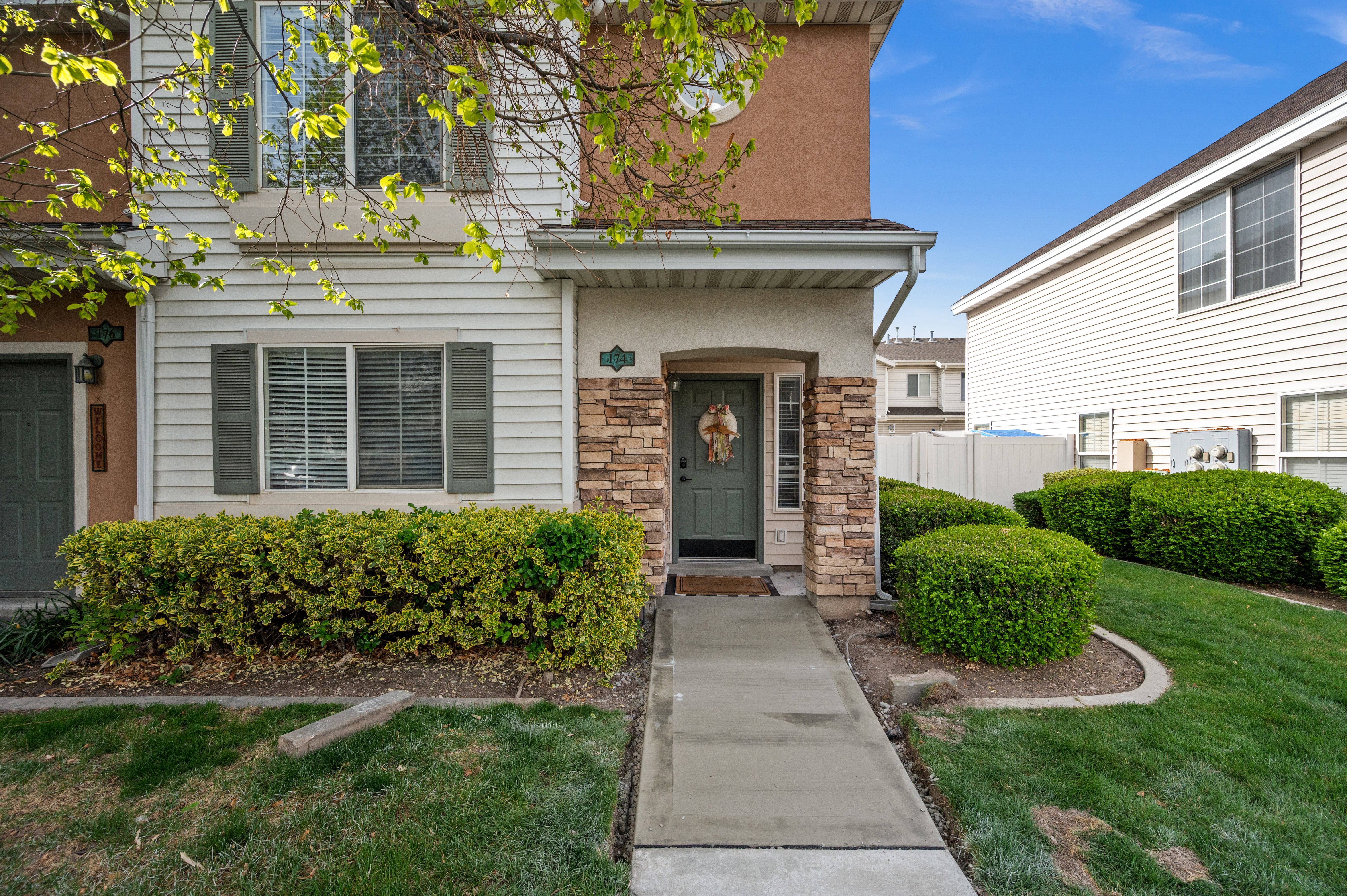 Entrance to property with stone siding, a lawn, and stucco siding