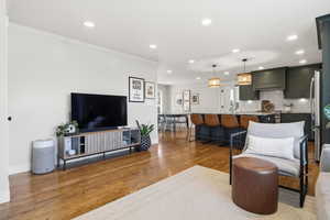 Living room with dark wood-type flooring, recessed lighting, and crown molding