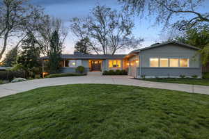 Ranch-style house with brick siding, curved driveway, an attached garage, a chimney, and board and batten siding