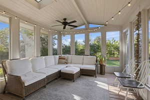 Sunroom / solarium with plenty of natural light, lofted ceiling with beams, wood finished floors, track lighting, and wooden ceiling