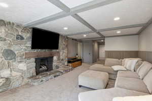 Carpeted living area featuring wood walls, wainscoting, a fireplace, recessed lighting, and a textured ceiling