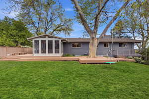 Back of house featuring a deck, a sunroom, brick siding, and a shingled roof
