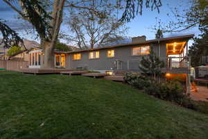 Back of house at dusk with a wooden deck, a chimney, and brick siding