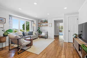 Living room featuring recessed lighting, light wood-type flooring, and ornamental molding
