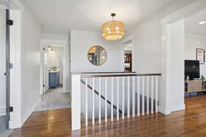 Corridor with wood finished floors, recessed lighting, an upstairs landing, and crown molding