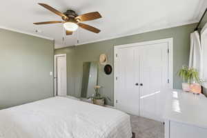 Bedroom with crown molding, light colored carpet, and a ceiling fan
