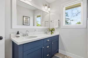 Full bath featuring double vanity and baseboards