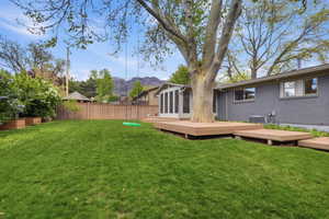 Fenced backyard featuring a deck with mountain view and a sunroom