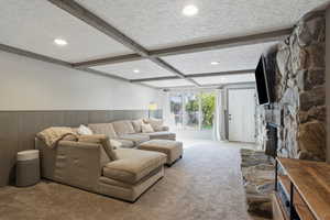 Carpeted living room with a fireplace, beam ceiling, a textured ceiling, a wainscoted wall, and recessed lighting