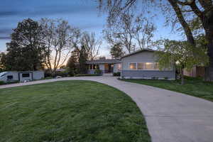 Ranch-style home with brick siding, curved driveway, and a front yard