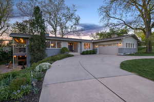 View of front of property with curved driveway, brick siding, and a garage