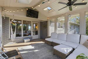 Sunroom / solarium with a skylight, wood finished floors, ceiling fan, outdoor seating, and beam ceiling