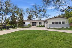 Ranch-style house with brick siding, curved driveway, a garage, and a chimney