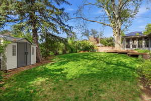 Fenced yard featuring a deck and a storage shed