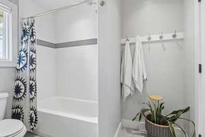 Bathroom with toilet and shower / bath combo with shower curtain