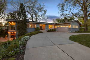 View of front of property with brick siding, concrete driveway, an attached garage, and a chimney