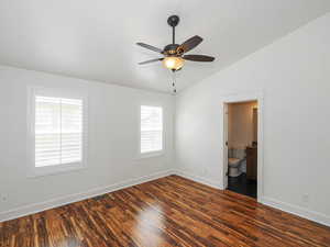 Empty room with dark wood-type flooring, vaulted ceiling, and a ceiling fan