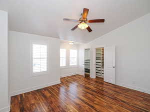 Unfurnished bedroom featuring dark wood-type flooring, ceiling fan, and lofted ceiling