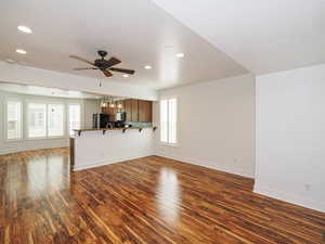 Unfurnished living room with dark wood-style floors, ceiling fan, a textured ceiling, and hanging lights