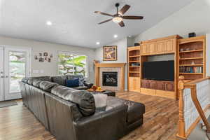Living room with recessed lighting, light wood-style floors, ceiling fan, vaulted ceiling, and a tiled fireplace
