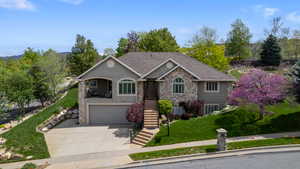 View of front of property featuring stone siding, an attached garage, stucco siding, a front yard, and concrete driveway