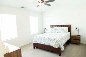 Bedroom with light carpet, ceiling fan, and lofted ceiling