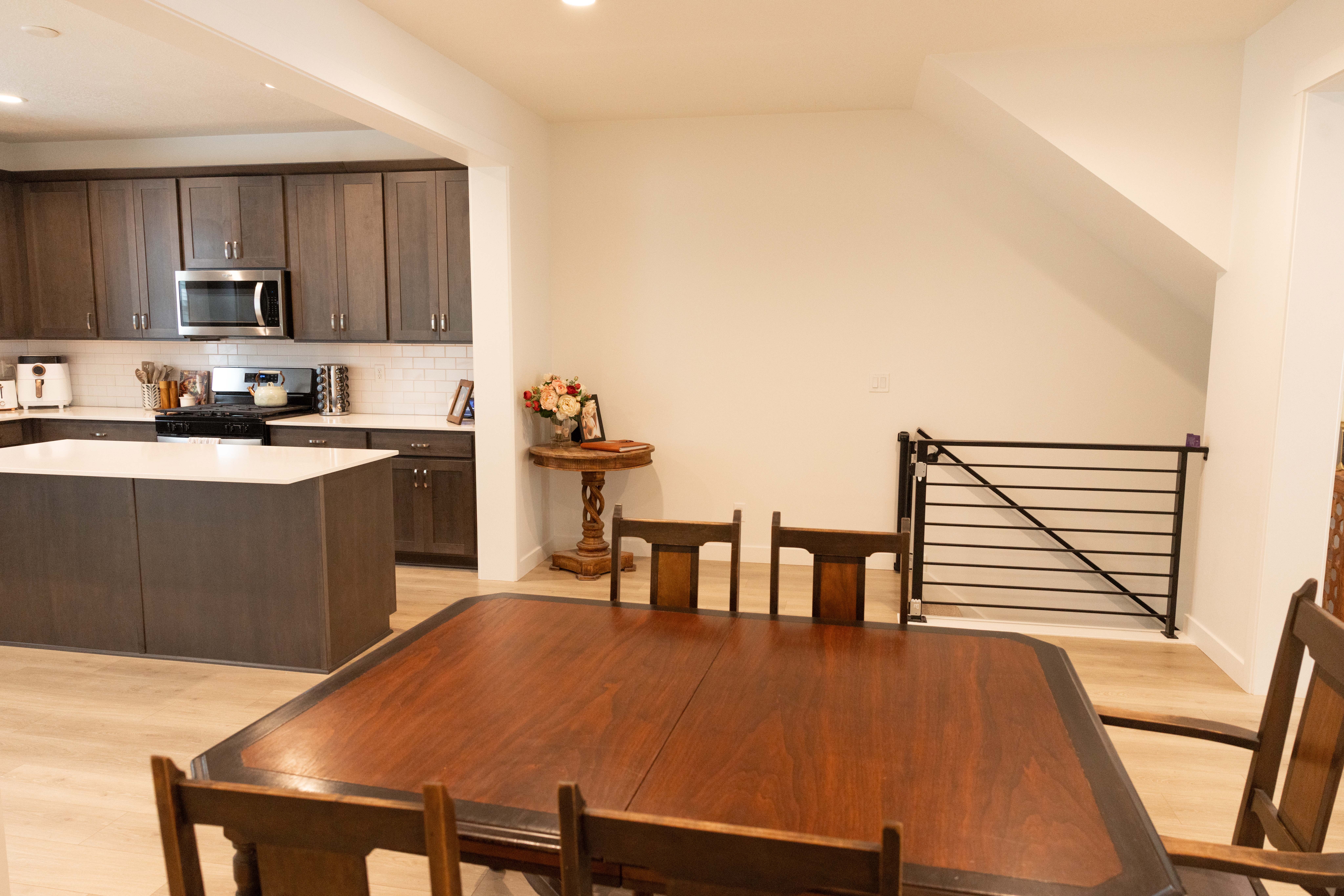 Kitchen featuring dark wood finish cabinets, light wood-style floors, stainless steel appliances, a center island, and tasteful backsplash