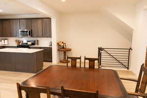 Kitchen featuring dark wood finish cabinets, light wood-style floors, stainless steel appliances, a center island, and tasteful backsplash