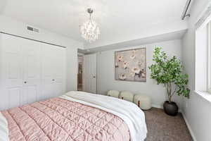 Carpeted bedroom with a chandelier and a closet