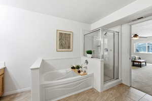 Ensuite bathroom featuring a stall shower, ceiling fan, a bath, light carpet, and light tile patterned floors