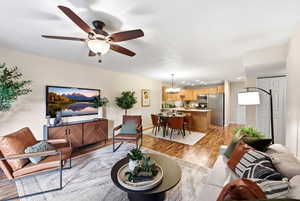 Living area featuring light wood finished floors, a ceiling fan, and a chandelier