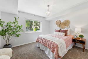 Bedroom with suspended lighting and dark colored carpet