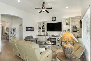 Living area with vaulted ceiling, a ceiling fan, arched walkways, light wood-style floors, and recessed lighting