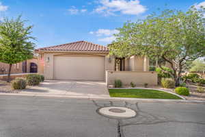 View of front facade with stucco siding, driveway, a garage, and a tile roof