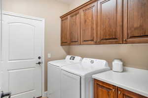 Laundry area featuring separate washer and dryer and cabinet space