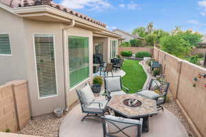 Fenced backyard with a patio area, an outdoor living space with a fire pit, and grilling area