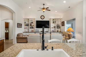 Living area featuring ceiling fan, recessed lighting, arched walkways, vaulted ceiling, and wood finished floors