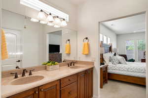 Full bath with double vanity, light carpet, and connected bathroom